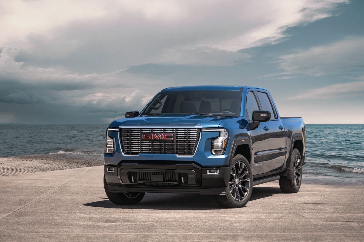 Blue 2027 GMC Sierra 1500 Denali parked on a concrete pier beside open water