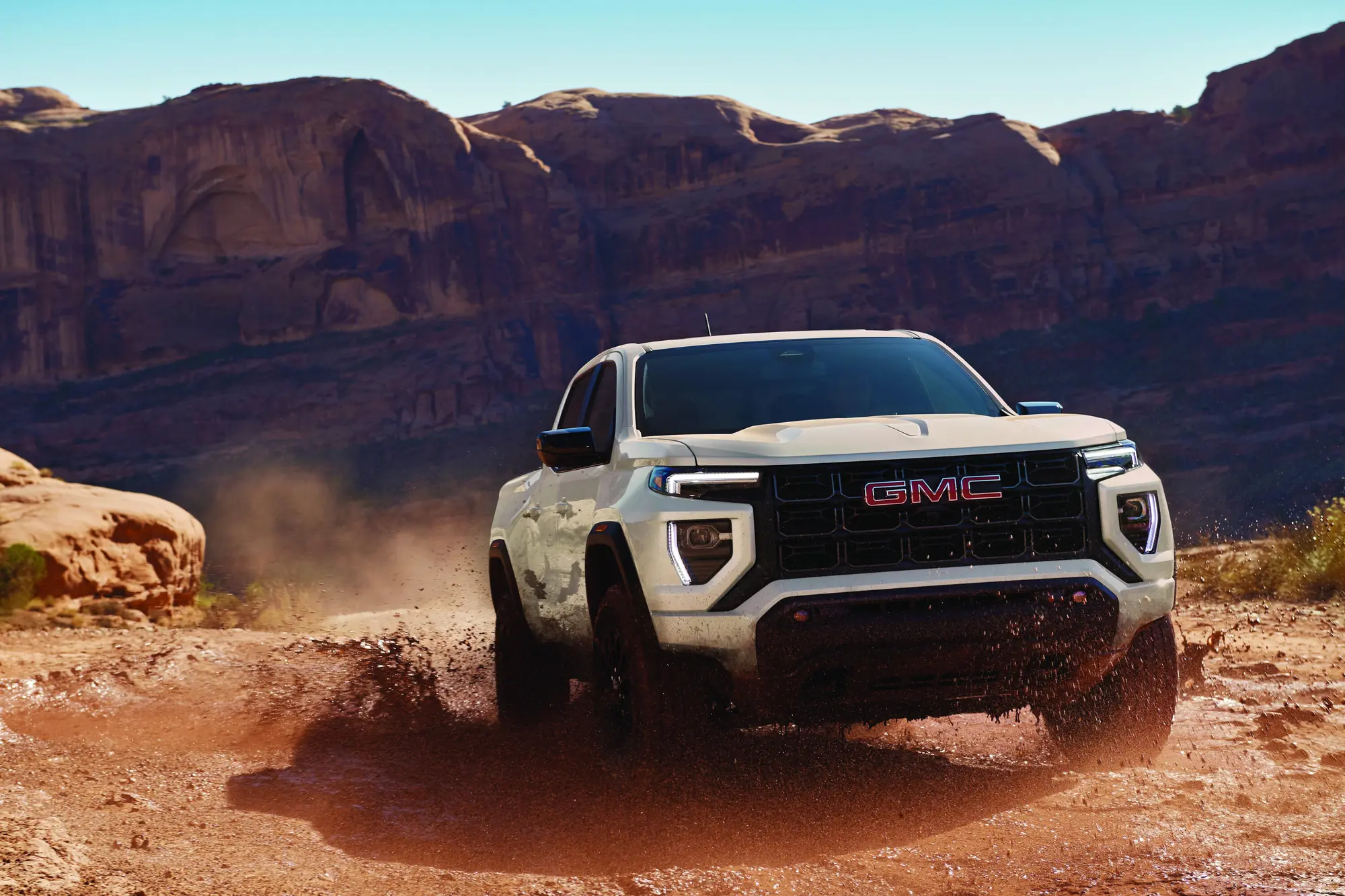2027 GMC Canyon Elevation in Coastal Dune driving through mud in the desert