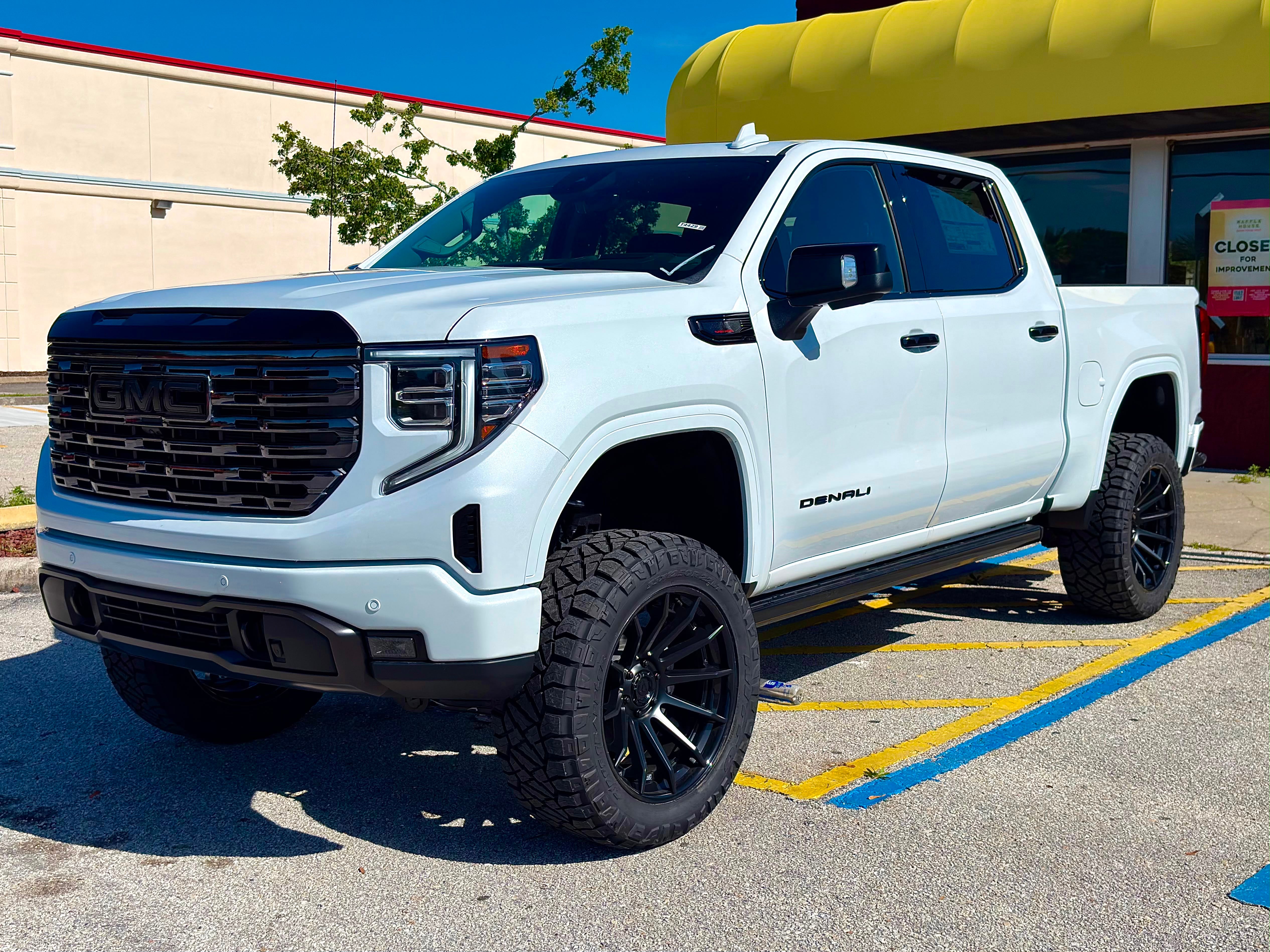 Lifted white GMC Sierra 1500 Denali front three quarter on black wheels in Tampa