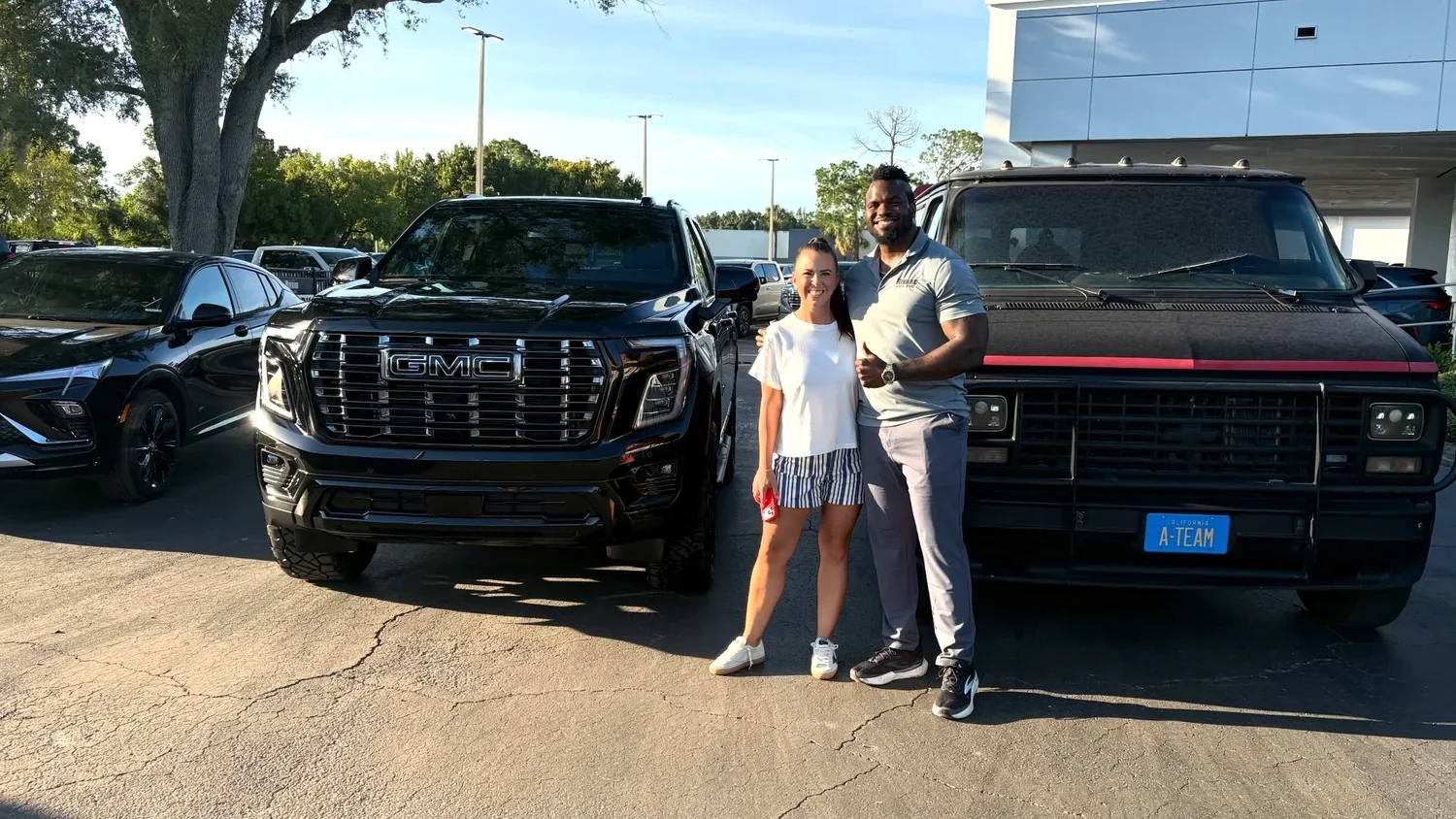 Ashley with her blacked out GMC Yukon build beside the A-Team van at Rivard Buick GMC