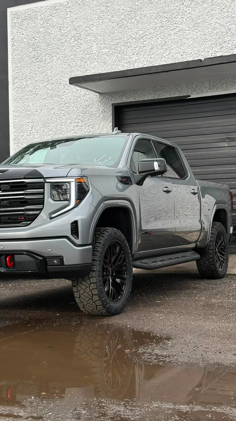 Lifted grey GMC Sierra 1500 AT4 on black wheels and Nitto tires