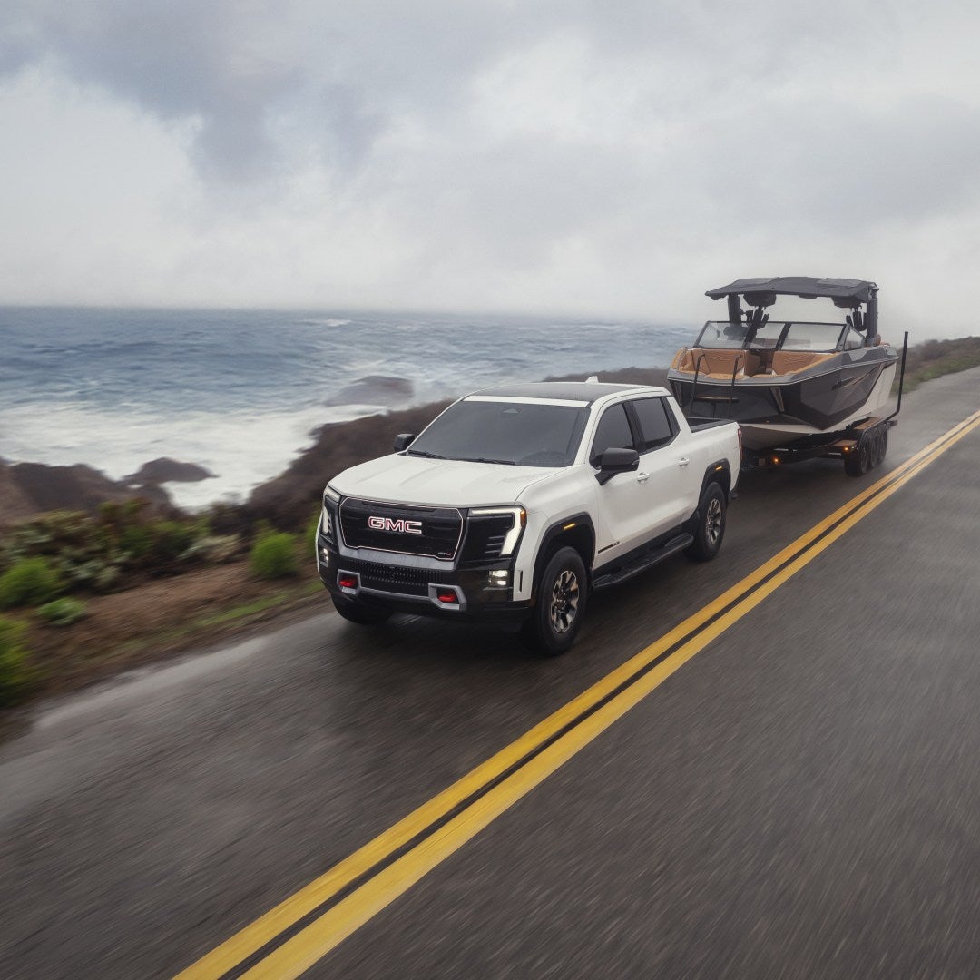 2026 GMC Sierra EV pulling a boat trailer along the coast