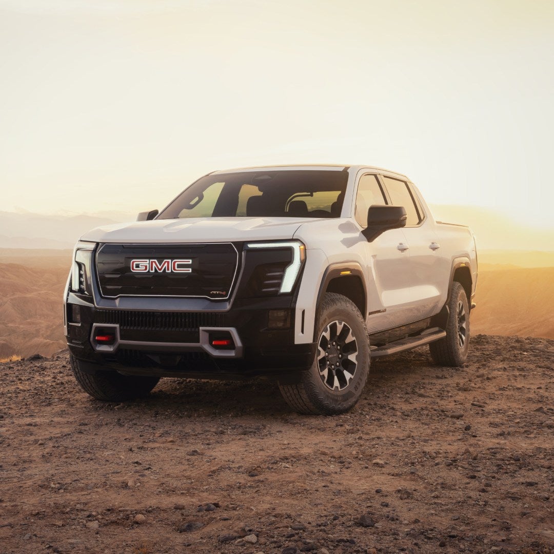 2026 GMC Sierra EV AT4 parked on desert terrain at sunset