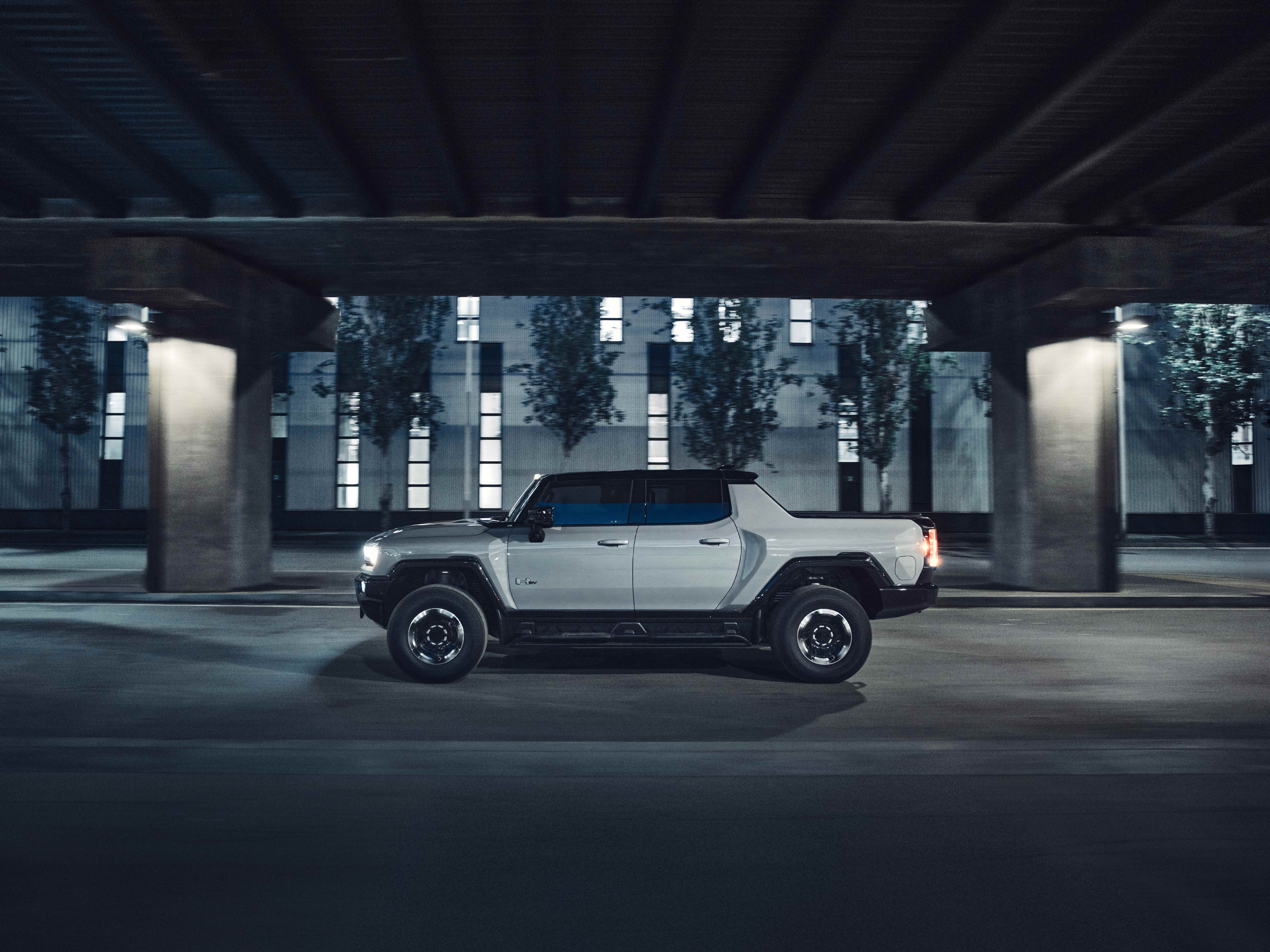 2026 GMC Hummer EV Pickup side profile driving under a city overpass