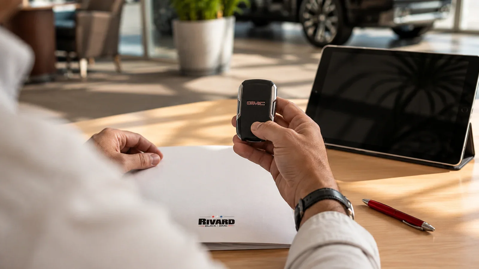 Customer holding a GMC key fob at a Rivard Buick GMC finance desk